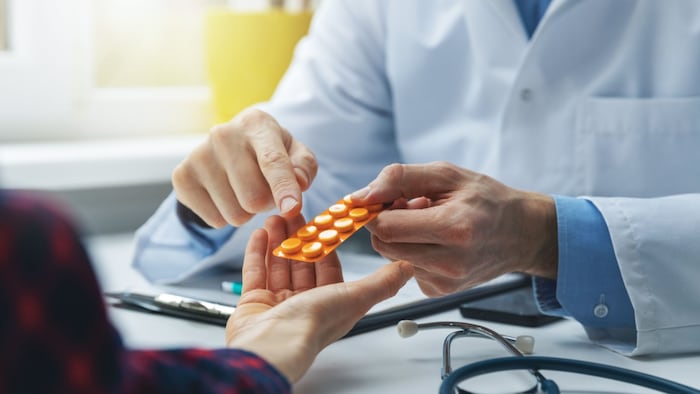 doctor prescribing medicine sitting at the desk in the clinic office
