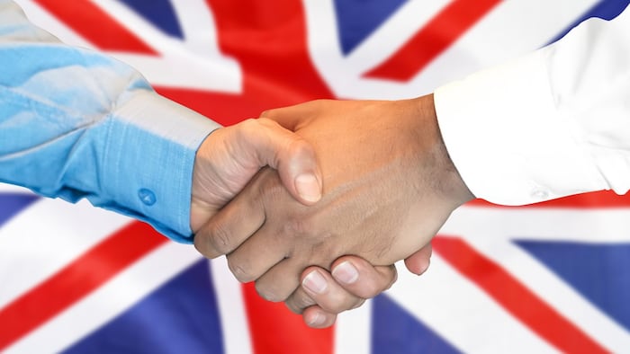 Handshake with UK flag in background